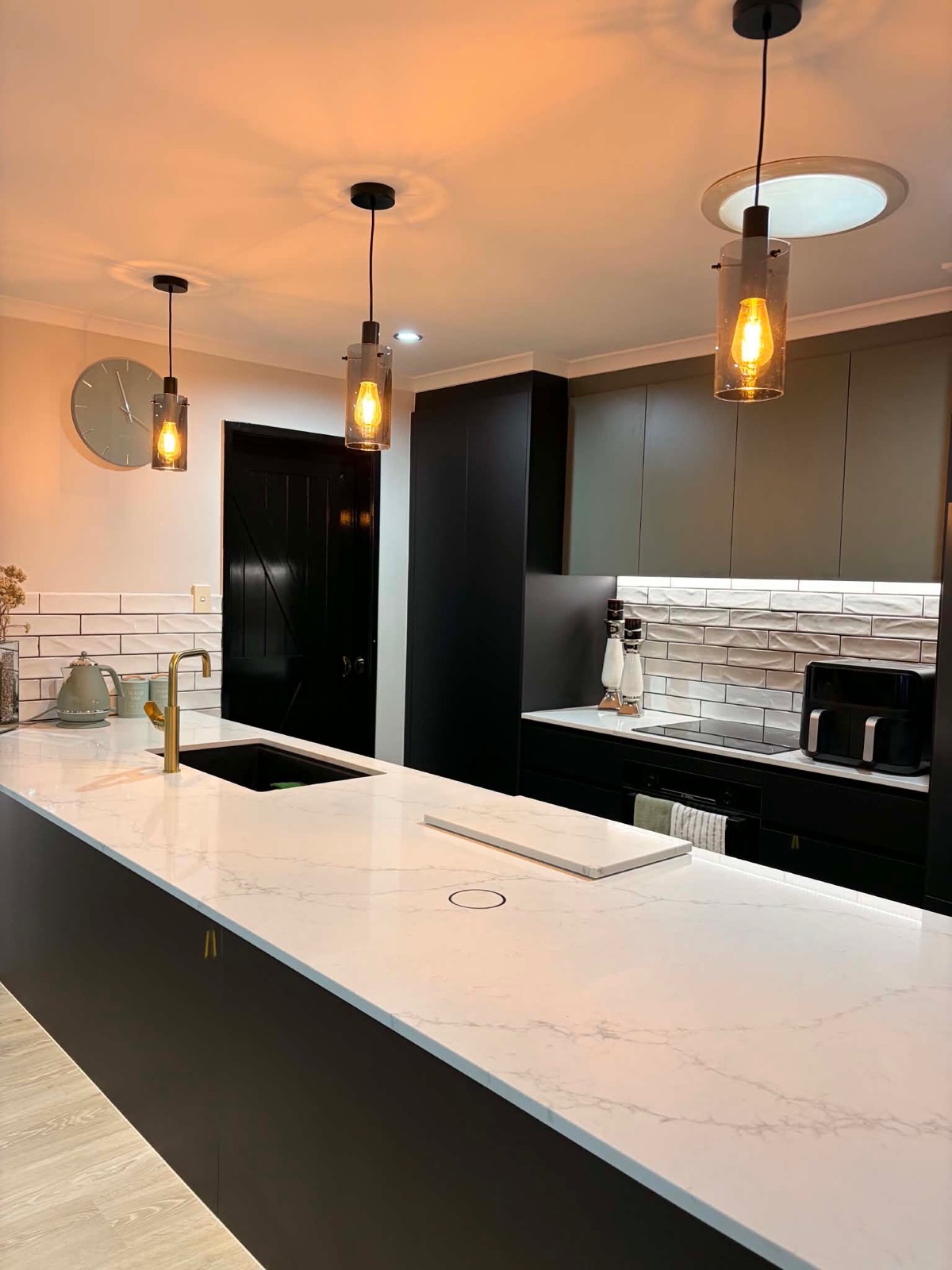 Kitchen island benchtop with pendant lighting and gold tapware